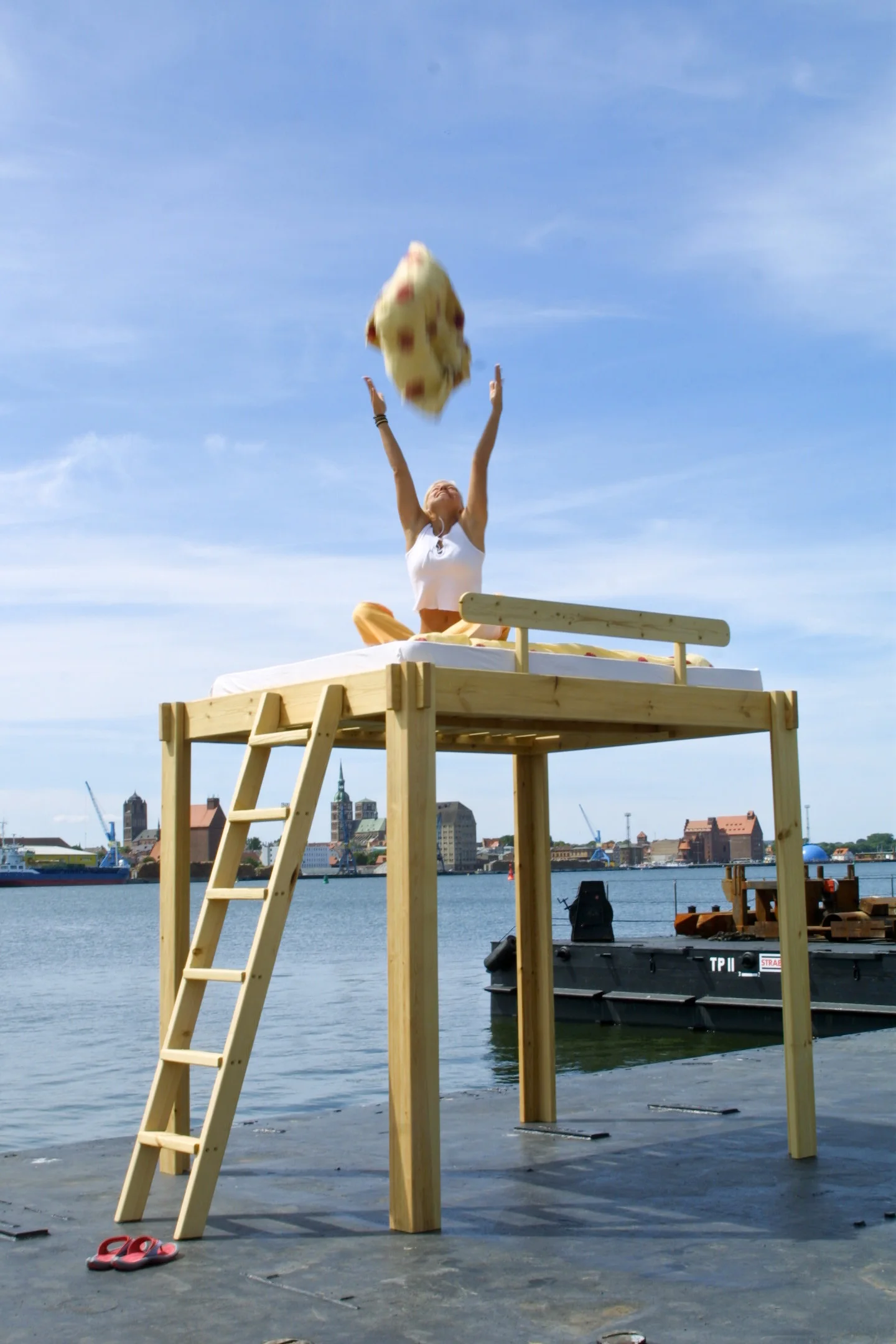 Eine Frau präsentiert ein handgefertigtes Hochbett am Stralsunder Hafen.