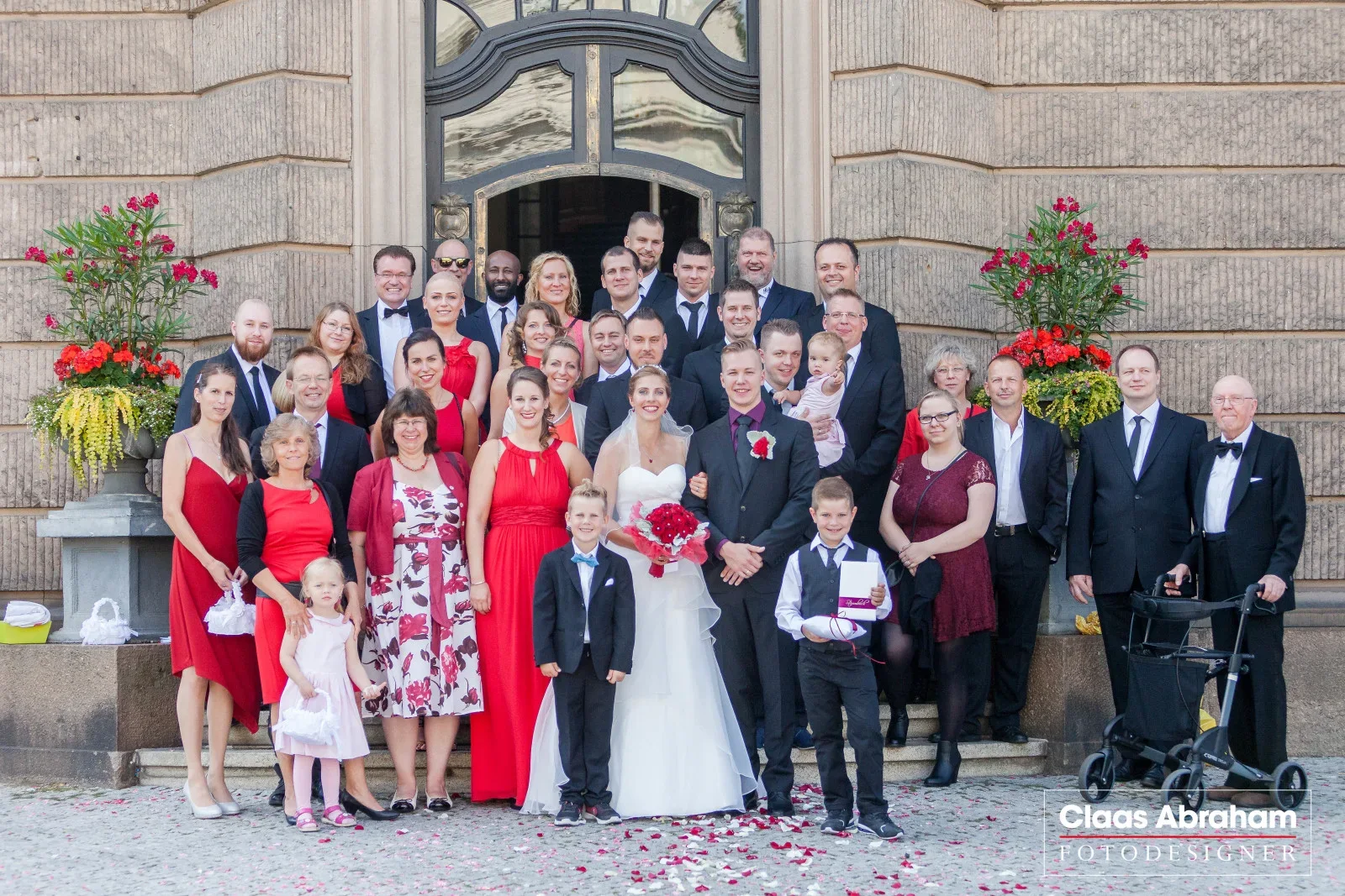 Das Hochzeitspaar mit seiner Hochzeitsgesellschaft vor einem historischen Gebäude.