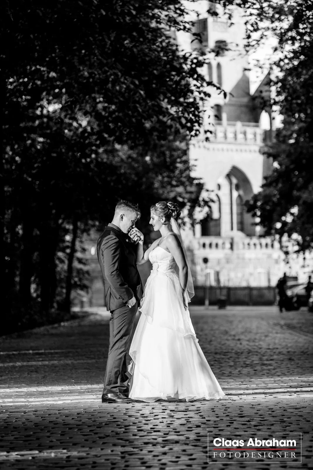 Ein Hochzeitspaar steht sich vor einer historischen Kulisse ruhig gegenüber.