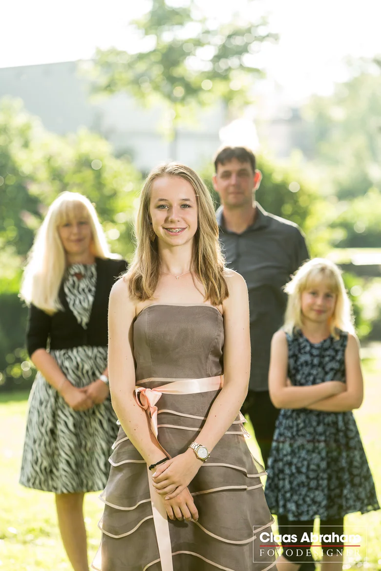 Jugendliche im Festkleid mit ihrer Familie bei einem Jugendweihe-Gruppenfoto.